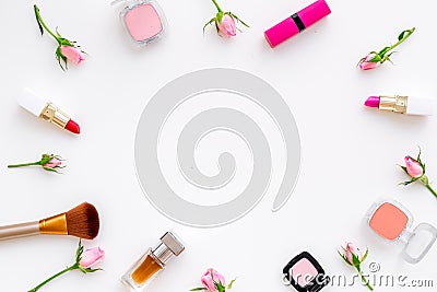 Rose, pink decorative cosmetics frame. Lipstick, bulk, eyeshadow and small rose flowers on white background top view Stock Photo