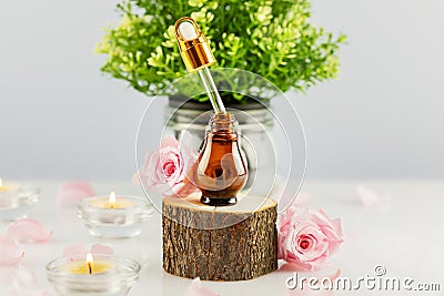 Rose serum on wooden podium, rose petals and candles Stock Photo