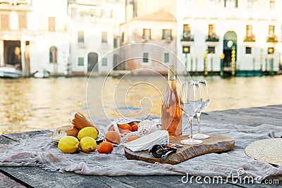 Rose wine, fruits and snacks on the wooden pier during picturesque picnic on the wooden dock Stock Photo