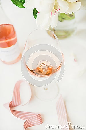 Rose wine in glass and bottle, pink ribbon, peony flowers Stock Photo