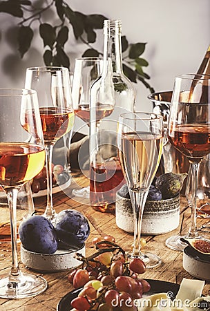 Rose wine glasses and bottles on table served for festive dinner party with different kinds of appetizers and fruits Stock Photo