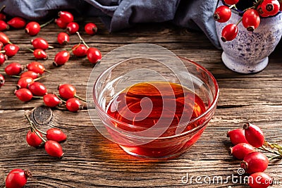 Rosehip seed oil in a bowl with fresh rosehips Stock Photo