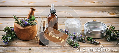 Rosemary aromatherapy. Essential oil and cosmetics, tag with text rosemary, banner. Wooden table background Stock Photo