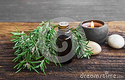 Rosemary aromatherapy oil with rosemary herb on wooden background with candle Stock Photo