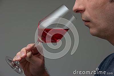 RosÃ© wine in glass being sniffed by unrecognizable Caucasian male. Close up studio shot, isolated on gray background Stock Photo