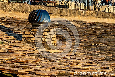 Rotating spinner chimney vent on stone roof Stock Photo