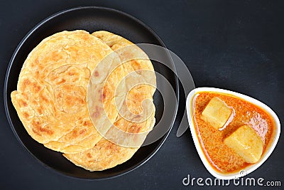 Roti parata or Roti canai served with potato curry sauce on black background. Stock Photo