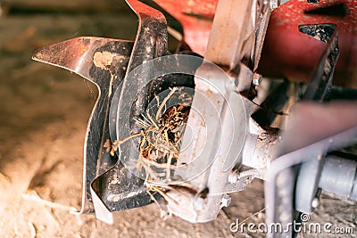 Rototiller of a walk-behind tractor with tangled dry grass close-up Stock Photo