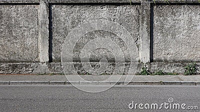 A rough concrete wall with a gray sidewalk and an asphalt road. Urban background for copy space Stock Photo