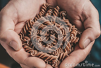 Rough masculine hands hold Italian pasta Stock Photo