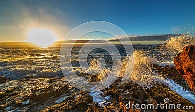 Rough sea by Sardinia rocky shore at sunset Stock Photo