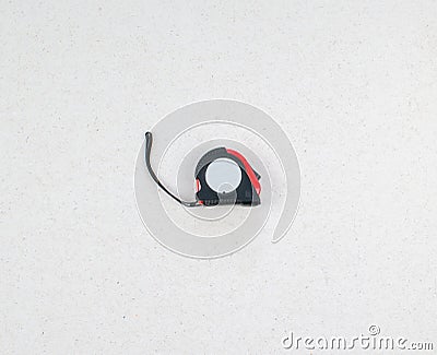 Roulette isolated on a light background close up. Black and red construction tape measure. Meter with a lace. Stock Photo