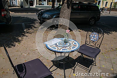 Round cafe table on sidewalk in front of restaurant Editorial Stock Photo