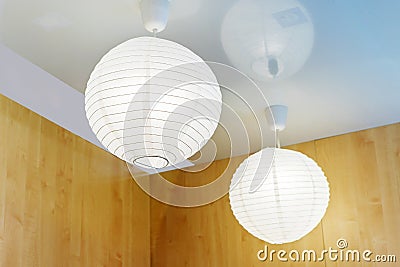 Round ceiling lampshades made of fabric on a wooden wall background. Home lighting close-up Stock Photo