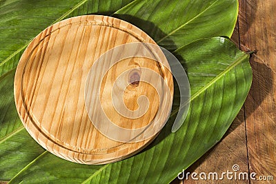 Round chopping board on bijao sheets - Calathea lutea Stock Photo