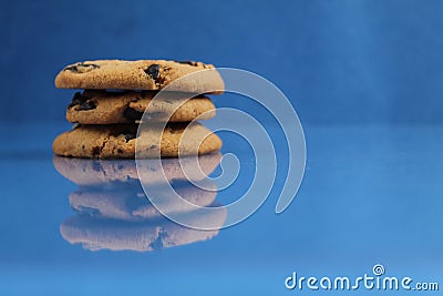 A round cookie with chocolate drops is stacked on top of each other on a blue bright saturated background with a reflection side v Stock Photo