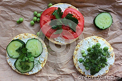 Round crispy corn sandwiches with vegetables toppings. Puffed corn cakes with cream cheese, tomatoes, cucumbers, and peas on craft Stock Photo