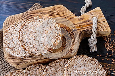 Round dietary loaves of airy buckwheat on wooden background with buckwheat scattered around, vintage board and burlap. top view Stock Photo