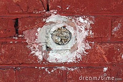 Round electrical outlet box without wires filled with paper mounted inside red brick wall Stock Photo