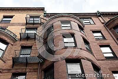 Round front of brownstone city housing, rusticated stone trim and metal balconies Stock Photo