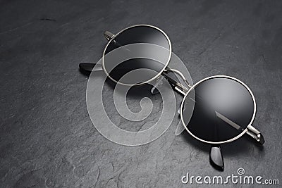 Round gray metal sunglasses on on black slate background Stock Photo
