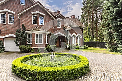 Round hedge and a small statue in the middle of a cobblestone dr Stock Photo