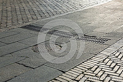 Round iron manhole with hatches rectangular gratings of the drainage system on the road. Stock Photo