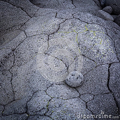 A round lava stone perfectly fitted into a small cavity in vulcanic rock, Hvaleyri beach, Iceland Stock Photo