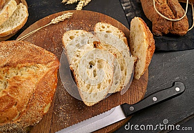 Fresh bread slice and cutting knife on rustic table Concept of homemade bread, natural farm products, domestic production. Healthy Stock Photo