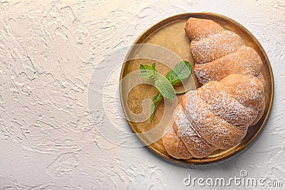 Round metal tray with tasty croissants on light textured background Stock Photo