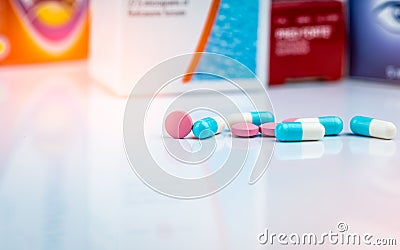Round pink tablets pill and white-blue capsule pills on blurred background of drug packaging. Painkiller medicine. Drug use Stock Photo
