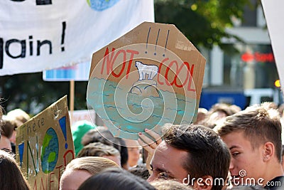 Round protest sign with polar bear on melting ice saying ` Not cool` held up by young people during Fridays for future strike for Editorial Stock Photo