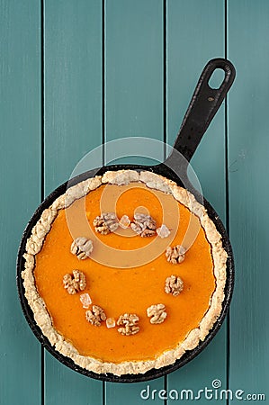 Round pumpkin pie with wallnuts and crystal sugar in cast iron s Stock Photo