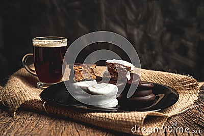 Regular and white chocolate cookies on a black plate with a tea on the table Stock Photo