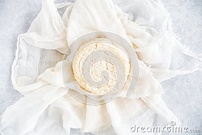 Round Soft Cow Cheese on Muslin Cloth and Blue Background Stock Photo