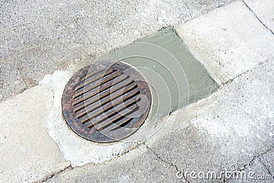 Round storm drain grate over just repaired manhole on the road Stock Photo