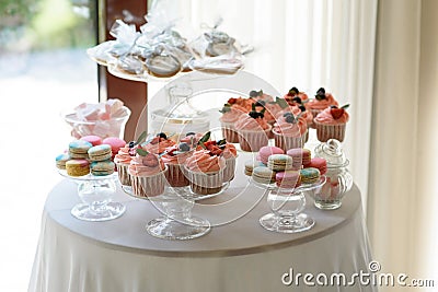 Round table with luxurious cupcakes and macaroons Stock Photo