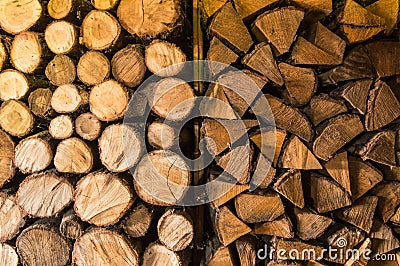 Round and triangular cutted or chopped firewood, folded in stacks in the storage, ready to use in fire, fireplace or campfire. Tex Stock Photo