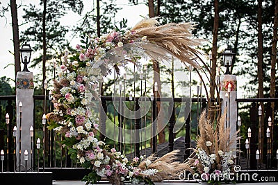 Round wedding arch from branches decorated with flowers and decor around it. Stock Photo