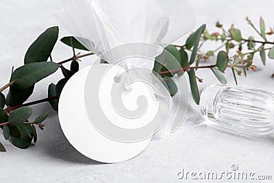 Round white gift tag mockup with eucalyptus leaves on grey background, label tag mockup, Wedding favor tag Stock Photo