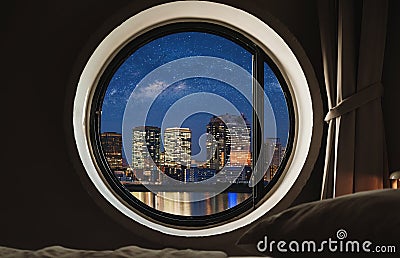 Round window frame in bedroom at night with city view Stock Photo