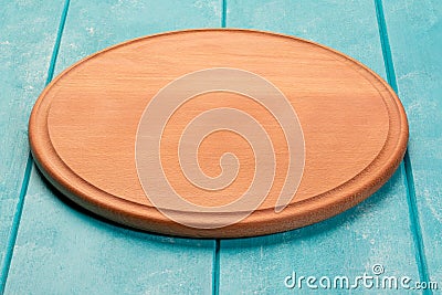 Round wooden cutting board for pizza on blue wooden table. Full depth of field. Mockup for food project Stock Photo