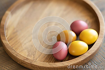 On a round wooden tray are five brightly colored Easter eggs and space for text. Stock Photo