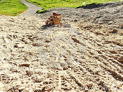 Toy rover wheel prints in the sand road, green field in the perspective Stock Photo