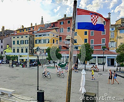 A view of the waterfront in the old town of Rovinj, Croatia. People are walking along the boardwalk with the croatian flag flying Editorial Stock Photo