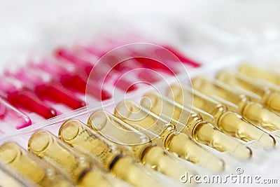 A row of ampoules with yellow medicine. Quarantine during the coronavirus pandemic. Vaccine against the virus. Close-up Stock Photo