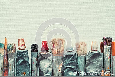 Row of artist paintbrushes and paint tubes closeup on artistic canvas. Stock Photo