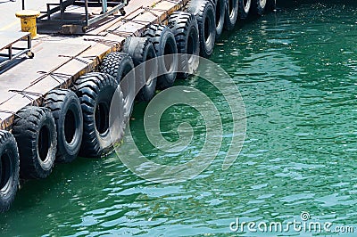 Row of black car tires used as boat bumpers Stock Photo