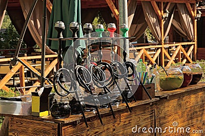 A row of black hookahs standing on a brown wooden table of an open summer restaurant Stock Photo