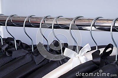 Row of black soft silk hangers with alone elegant white one between there. Luxury fashionable boutique concept Stock Photo